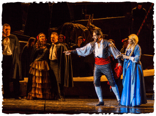 A man in a white top stands next to a woman in a blue dress