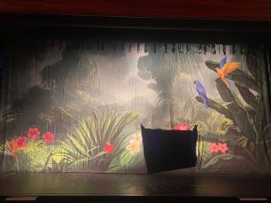 A printed cloth of a tropical forest with birds and flowers