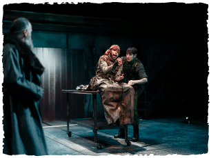 2 people huddled together sat on table, looking scared