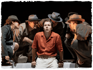 One man sat on table, other men leaning in