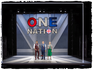 3 actors in front of a sign that says One Nation