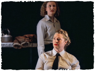 Woman in shirt and tie sat down, woman stood behind her