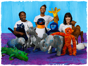 three performers sit with animal puppets from the show