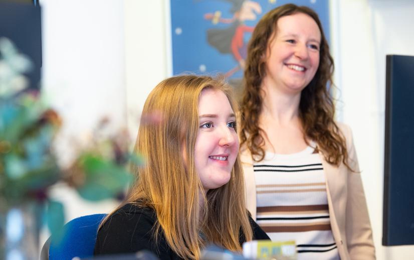 Two women at box office smile at a customer