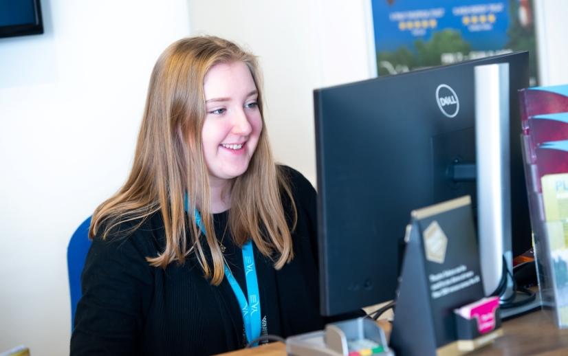 women at box office smiling looking at computer screen