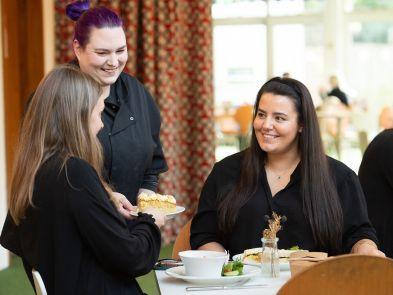 Couple sat at a table with cake and food being brought by our chef