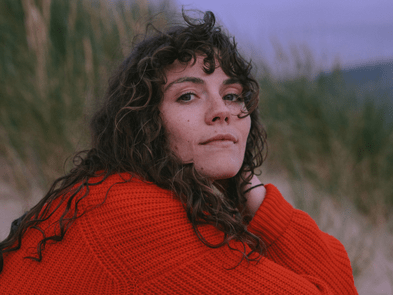 Ellie gowers in a red jumper on a sandy beach