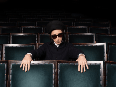 John Cooper Clark sat in dark room in row of seats