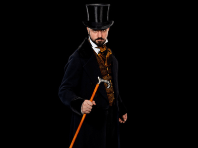 A man in a black suit and top hat holds a walking stick looking sterm