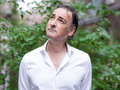 Alistair McGowan standing in a garden wearing a white shirt