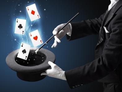 Cards coming out of a top hat and a hand holding a magic wand