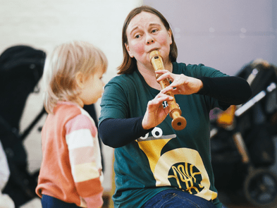A woman playing an instrument with a child watching