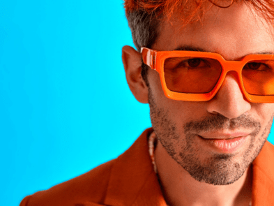 Ivo Graham with orange glasses, blue background